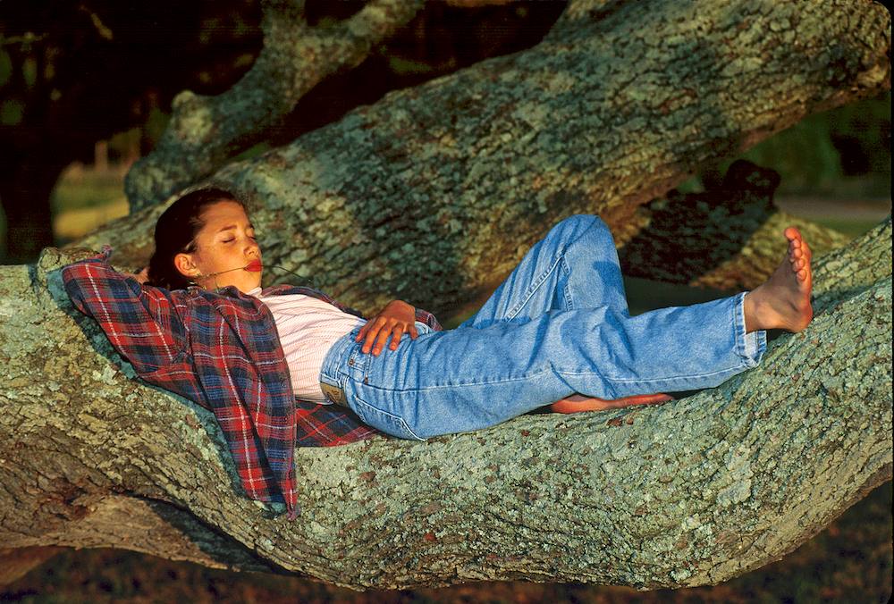 Girl relaxing on a tree trunk