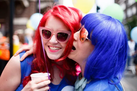 Two women in bright colored wigs having fun
