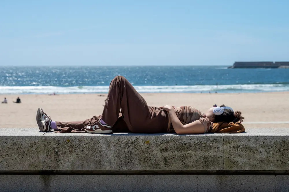 Young woman wearing headphones while laying near the beach