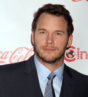Chris Pratt in a black jacket, dark shirt, and grey beanie on a mountain trail