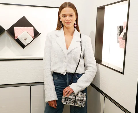 Valeria Lipovetsky smiles, wearing a white off-the-shoulder shirt and long flowy skirt, in a sunlit room