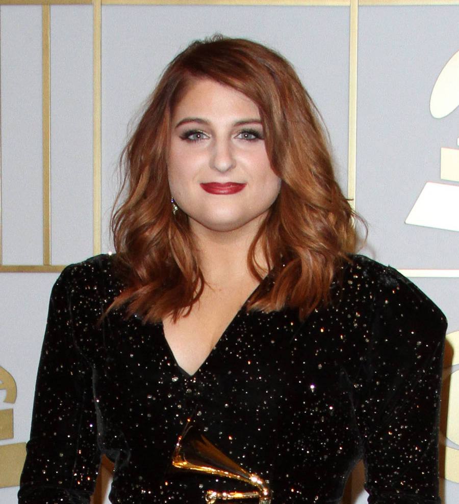 Meghan Trainor smiles, holding a Grammy award, with her father standing proudly beside her on stage