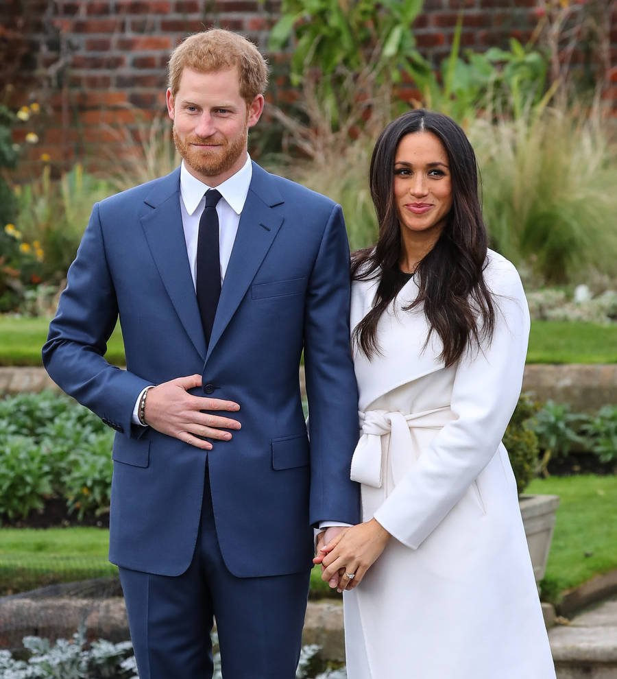 Meghan Markle smiles, looking over her shoulder with her hair down and a light-colored top