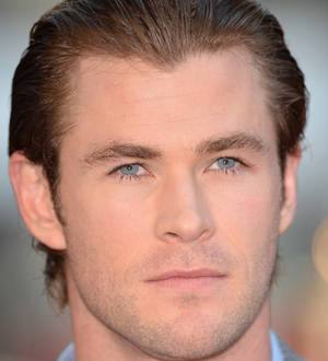 Chris Hemsworth in a car, looking through a side mirror, possibly focusing on driving