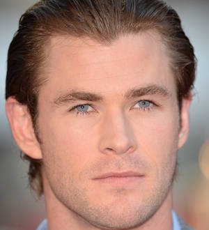 Chris Hemsworth in a car, looking through a side mirror, possibly focusing on driving