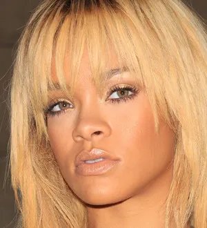 Rihanna with long red hair, wearing a white crochet top, and Chris Brown sporting a tattoo sleeve and sunglasses