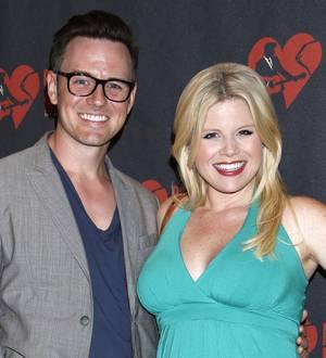 Megan Hilty smiles holding her newborn daughter wrapped in a pink blanket