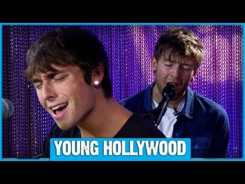 Member Wesley Stromberg from Emblem3 performs guitar and sings on stage, illuminated by blue light