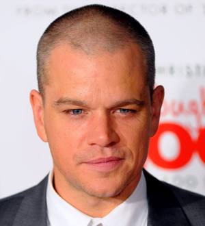 Matt Damon smiles, holding a bottle of olive oil with chef Gordon Ramsay at a charity event