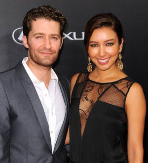 Matthew Morrison and Renee Puente embrace and kiss under an archway of flowers at their wedding ceremony