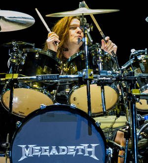 Megadeth drummer playing a drum kit on stage under purple stage lighting