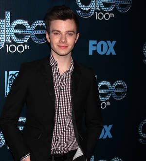 Actor Chris Colfer with short brown hair and a pink button-down shirt