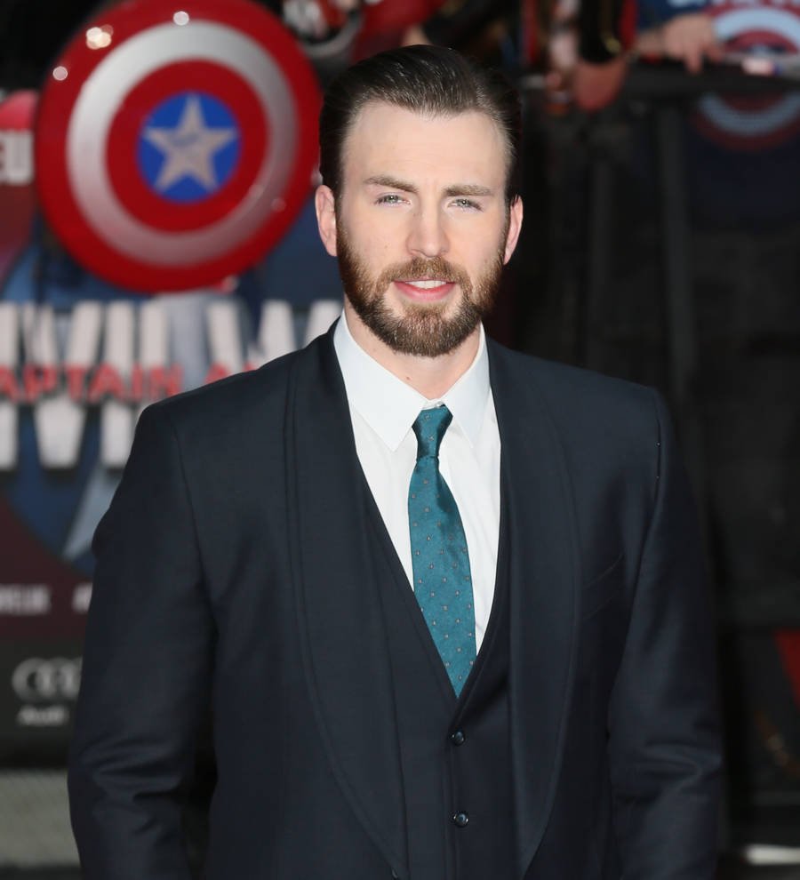 Chris Hemsworth on stage, his hand to his ear, smiling and looking out at the audience