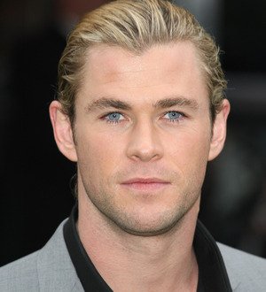 Chris Hemsworth grimaces dramatically as Kristen Stewart playfully punches him in the face