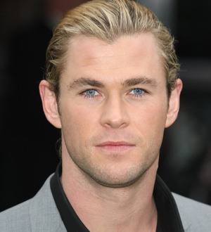 Chris Hemsworth grimaces dramatically as Kristen Stewart playfully punches him in the face
