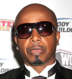 {"alt":"MC Hammer poses for a medium shot in a black suit and reflective gold sunglasses"}
