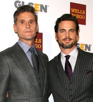 Matt Bomer smiles, accepting an LGBT award onstage, holding a microphone