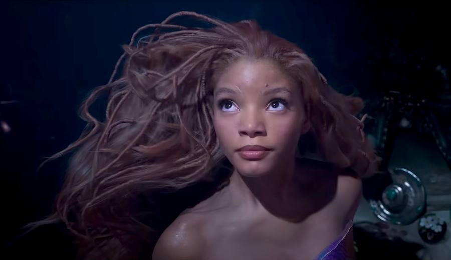Halle Bailey as Ariel, a Black woman with long red braids, swimming underwater