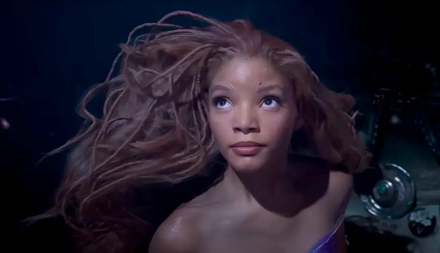 Halle Bailey as Ariel, a Black woman with long red braids, swimming underwater