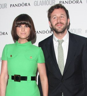 Chris O'Dowd standing outdoors, smiling and holding a small dog in his arms