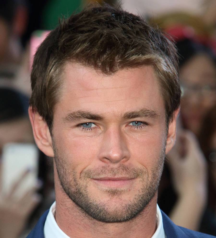 Chris Hemsworth on a red carpet, smiling broadly while posing for cameras