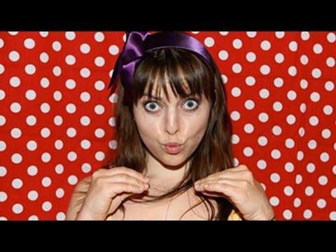 Olga Kay holds up a colorful digital camera, smiling broadly at the viewer