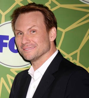 Christian Slater poses, looking directly at the camera with a serious expression