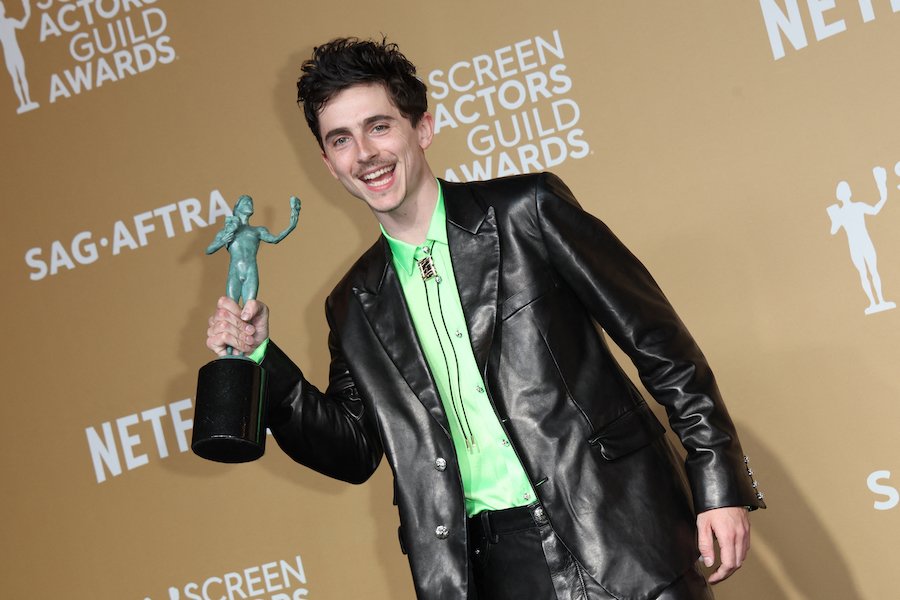 Timothée Chalamet smiling at the SAG Awards, wearing a black suit with a bow tie