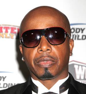 MC Hammer on a red carpet, head slightly tilted, wearing a black suit and sunglasses