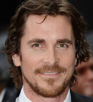 Christian Bale as Batman, in a close-up photo, wearing the dark, armored Batsuit