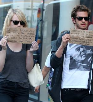 Andrew Garfield and Emma Stone hold up charity signs for snappers