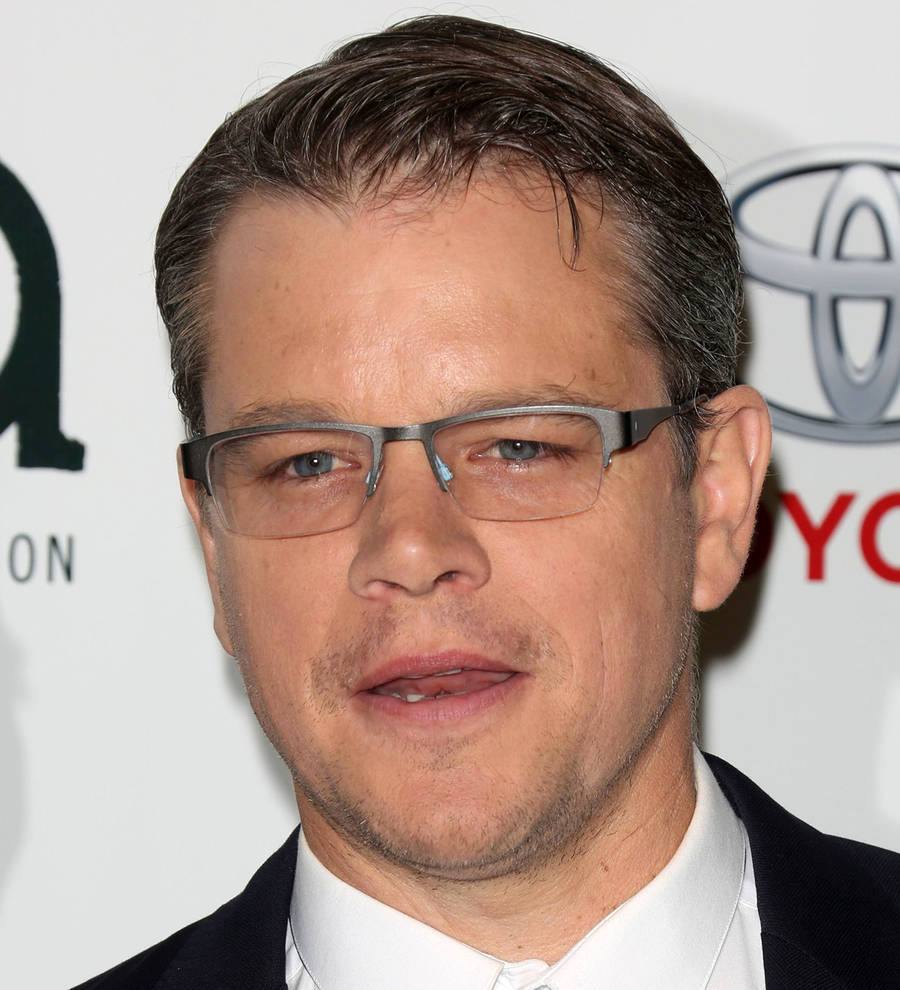 Matt Damon with short, slightly graying hair and a faint smile against a subtly blurred background