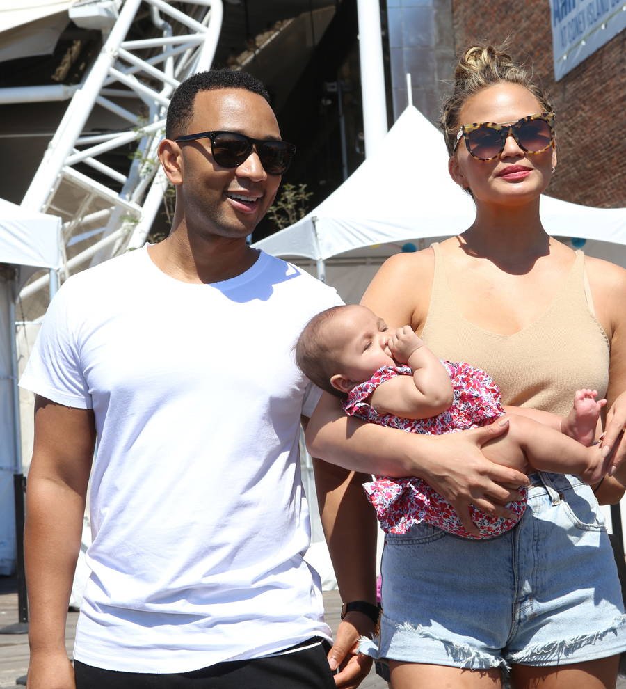 Chrissy Teigen and John Legend share a loving kiss, her arms around his neck, at a celebratory event