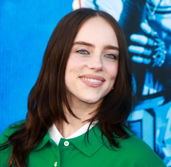 Billie Eilish on a red carpet, wearing an oversized black suit with white details
